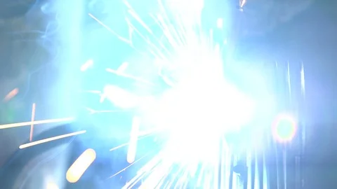 Worker`s hands making a spray of light blue sparkles while welding in a workshop Stock Footage 105448617
