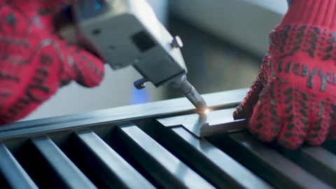 Worker's hands in red protective gloves using a handheld laser welding tool Stock Footage 345894676