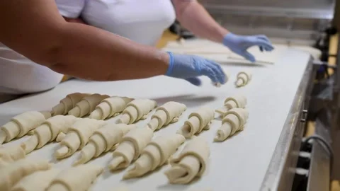 Workers hands rolling croissants on a white conveyor belt in an industrial .. Stock Footage 284468756