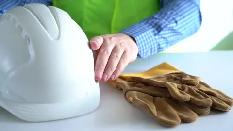 The worker's hands take a protective helmet and gloves from the table. Taking Stock Footage 166522698
