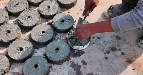 Worker's hands using a trowel to cast circular concrete spacers in molds. Stock Footage 326452681