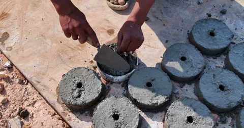 Worker's hands using a trowel to cast circular concrete spacers in molds. Stock Footage 326455005