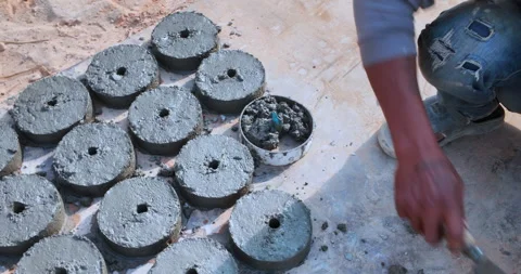 Worker's hands using a trowel to cast circular concrete spacers in molds. Stock Footage 326455979