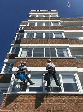 Workers have abseiled down a block of apartments to clean and paint exterior Stock Photos
