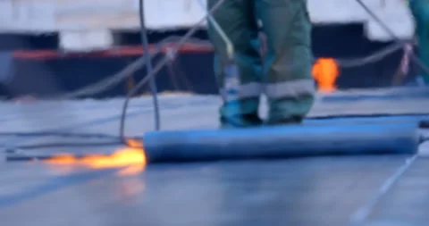 The workers heats the roll of ruberoid with the flame of a gas burner  Stock Footage 119627024