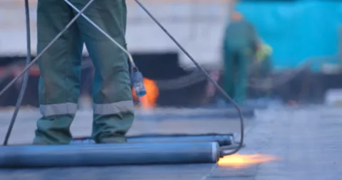 The workers heats the roll of ruberoid with the flame of a gas burner  Stock Footage 119627168