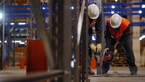 Workers in helmets fix rack carcass in warehouse slow motion Stock Footage 116974586