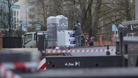 Workers in helmets secure wide crane straps to concrete slab Video stock 311622708
