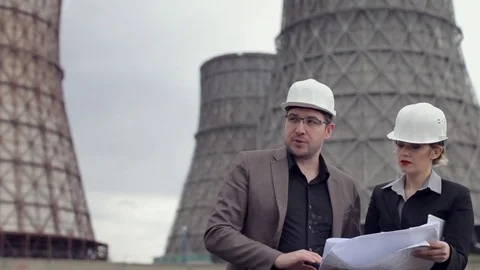 Workers in Helmets, Supervisors Examines Blueprints on Background of Nuclear Video stock 75443720