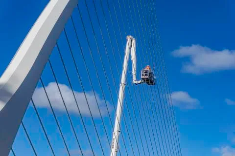 Workers, hoisted on a crane, doing maintenance work. Stock Photos