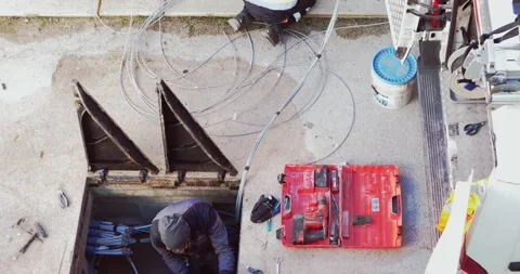 Workers insert fiber optic cables into the underground cable ducts to create Video stock 157958343