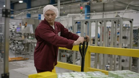Workers inspecting and carrying packed cosmetic boxes on trolley in factory Stock Footage 107961214