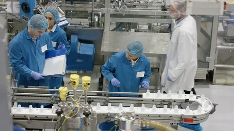 Workers inspecting cosmetic bottles and discussing at production line Stock Footage 107966992