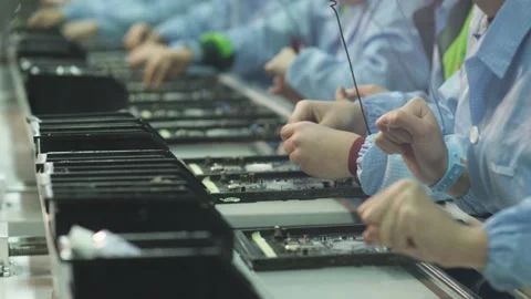 Workers install elements on an electronic circuit board at a TV factory Stock Footage 162364555