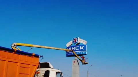 Workers install a large city sign in Minsk during a clear day in early spring Stock Footage 332477407