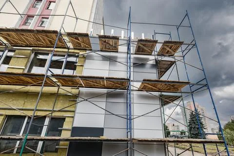 Workers install mineral wool insulation on the facade of a building while usi 写真素材