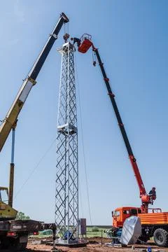 Workers install a wind generator using a truck crane and aerial platform Stock Photos
