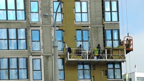 Workers install windows on new building in city construction site during daytime Stock Footage 331245217