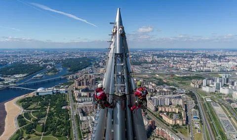 Workers installers at the height work at the top of skyscraper. Stock Photos