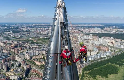 Workers installers at the height work at the top of skyscraper. Stock Photos