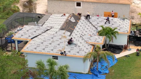 Workers installing asphalt shingles on suburban home rooftop. Roof construction Stock Footage 314800981