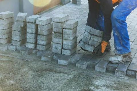 Workers installing concrete blocks on pavement in construction site during works Stock Photos