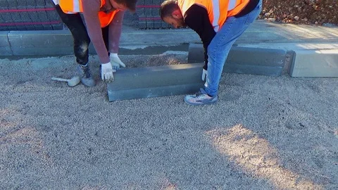 Workers installing concrete curb stone and using string with metal stakes to Stock-Footage 107178328