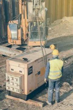 Workers installing electric generator at construction site Stock Photos