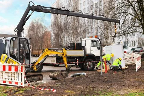 Workers installing electrical cabinet using crane and excavator near reside.. Stock Photos