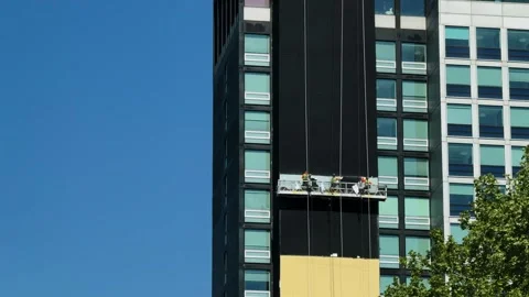Workers Installing Facade Panels on Suspended Platform at High-Rise in Stock Footage 334671599