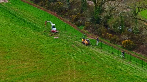 Workers Installing Fencing Along Lush Green Field with Machinery Video stock 336662653
