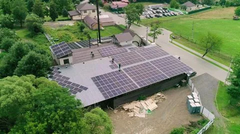 Workers installing PV solar panels on the roof of a house,which converts solar Stock Photos