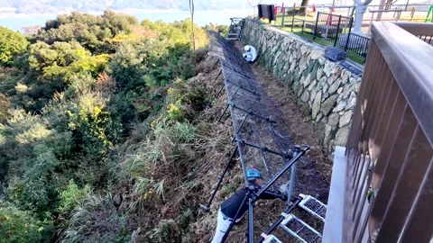 Workers installing rockfall protection netting beside mountain rock wall at Stock Footage 303340598