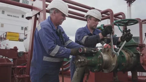 Workers in jumpsuits repair large pipe with silver spanners Stock Footage 147171637
