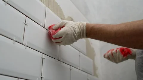 Workers lay ceramic tiles on the kitchen wall. Construction details, repair.. Stock Photos