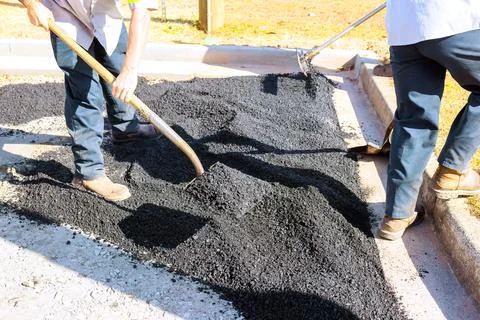 Workers lay down asphalt in parking lot Stock Photos