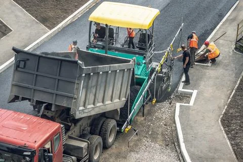 Workers lay a new asphalt coating using hot bitumen. Work of heavy machiner.. Stock Photos