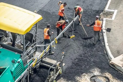Workers lay a new asphalt coating using hot bitumen. Work of heavy machiner.. Stock Photos