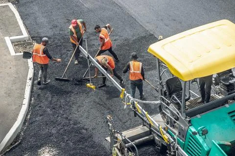 Workers lay a new asphalt coating using hot bitumen. Work of heavy machiner.. Stock Photos