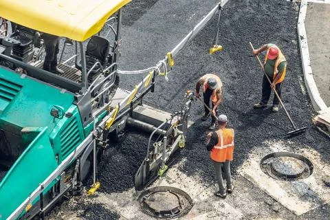 Workers lay a new asphalt coating using hot bitumen. Work of heavy machiner.. Stock Photos