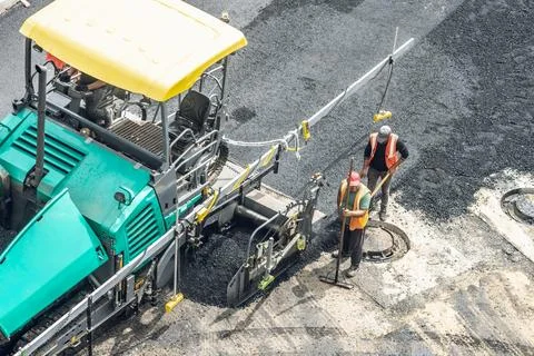 Workers lay a new asphalt coating using hot bitumen. Work of heavy machiner.. Stock Photos