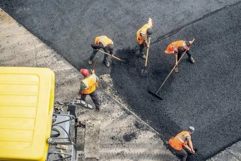 Workers lay a new asphalt coating using hot bitumen. Work of heavy machiner.. Stock Photos