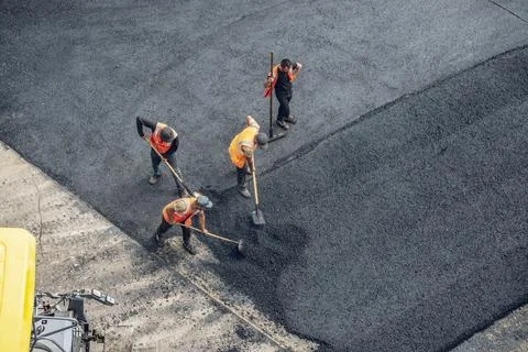 Workers lay a new asphalt coating using hot bitumen. Work of heavy machiner.. Stock Photos