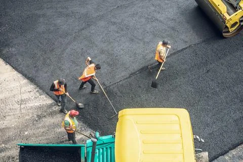 Workers lay a new asphalt coating using hot bitumen. Work of heavy machiner.. Stock Photos