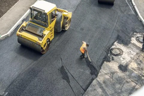 Workers lay a new asphalt coating using hot bitumen. Work of heavy machiner.. Stock Photos