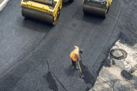 Workers lay a new asphalt coating using hot bitumen. Work of heavy machiner.. Stock Photos
