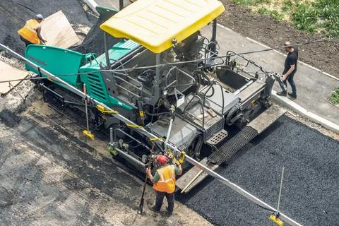 Workers lay a new asphalt coating using hot bitumen. Work of heavy machiner.. Stock Photos