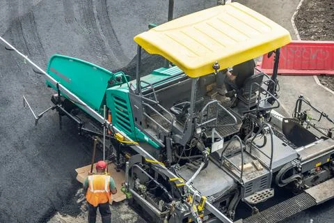 Workers lay a new asphalt coating using hot bitumen. Work of heavy machiner.. Stock Photos