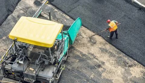 Workers lay a new asphalt coating using hot bitumen. Work of heavy machiner.. Stock Photos