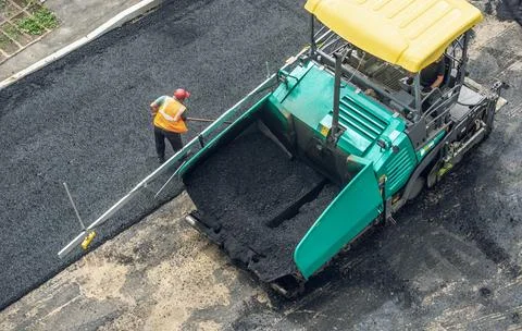 Workers lay a new asphalt coating using hot bitumen. Work of heavy machiner.. Stock Photos